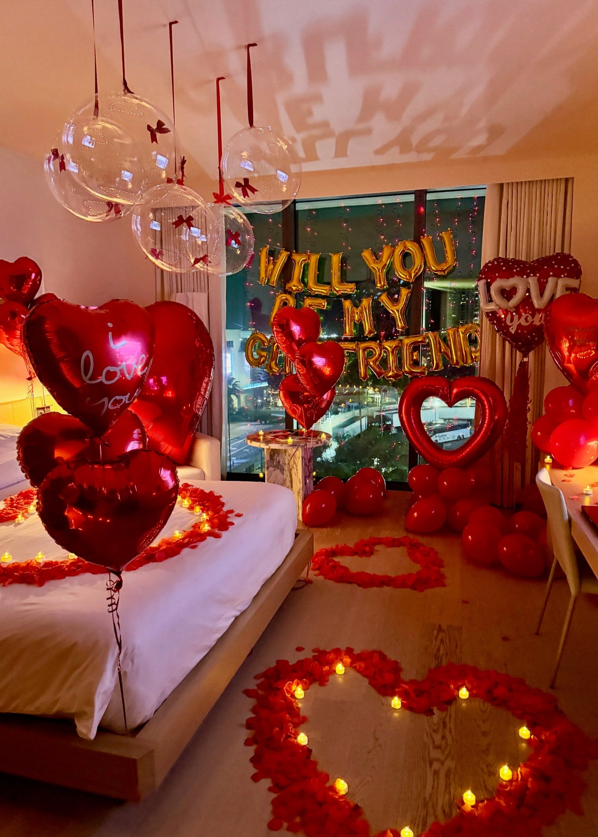Romantic "Will You Be My Girlfriend?" proposal setup with balloons, rose petals, heart decorations, and LED lights