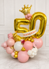 Luxury pink white and gold 50th birthday balloon arrangement with crown in Tampa
Custom double number balloon display with organic balloon base and floral accents
Pink and gold milestone birthday balloon arrangement with butterflies and flowers
Freestanding 50th birthday balloon bouquet with gold foil numbers and crown
Luxury custom number balloon arrangement by Party Galore Tampa