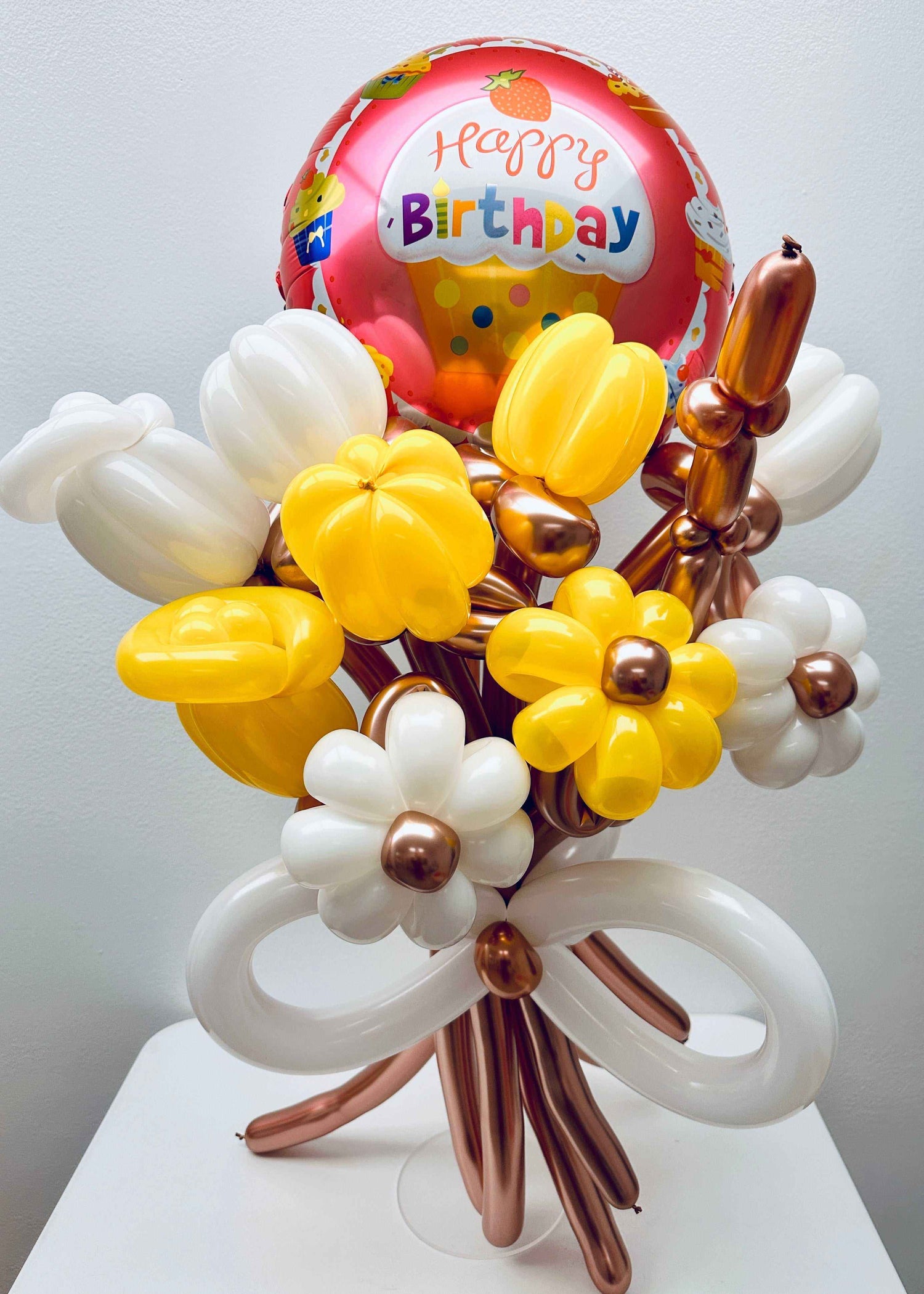 Surprise HBD Balloon Bouquet with yellow and white balloons shaped like flowers and a Happy Birthday foil balloon.