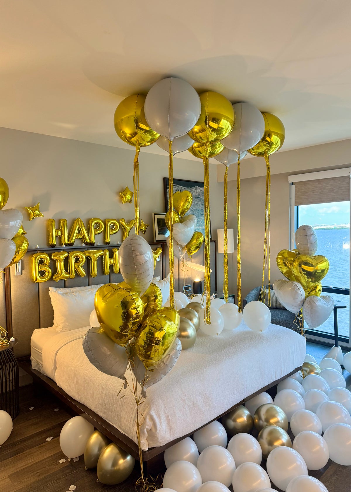 Romantic birthday room decor with gold foil letters and white balloons