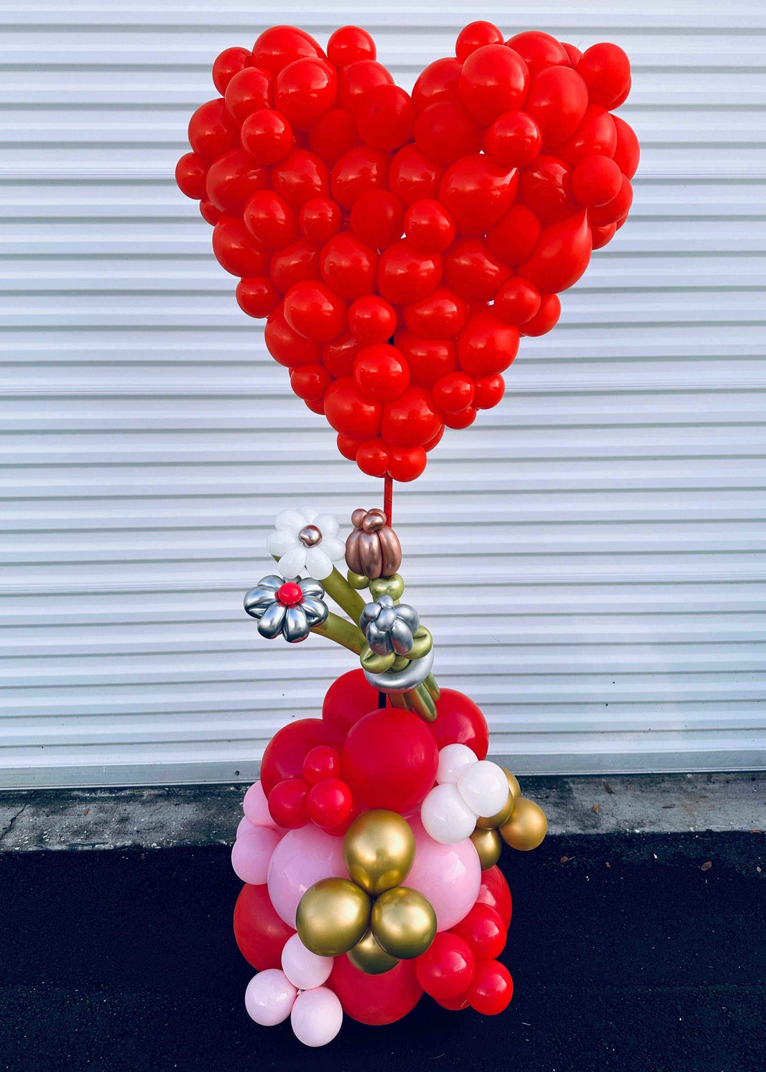 Large red hearts balloon bouquet with gold and white balloon accents, romantic helium love display for celebrations