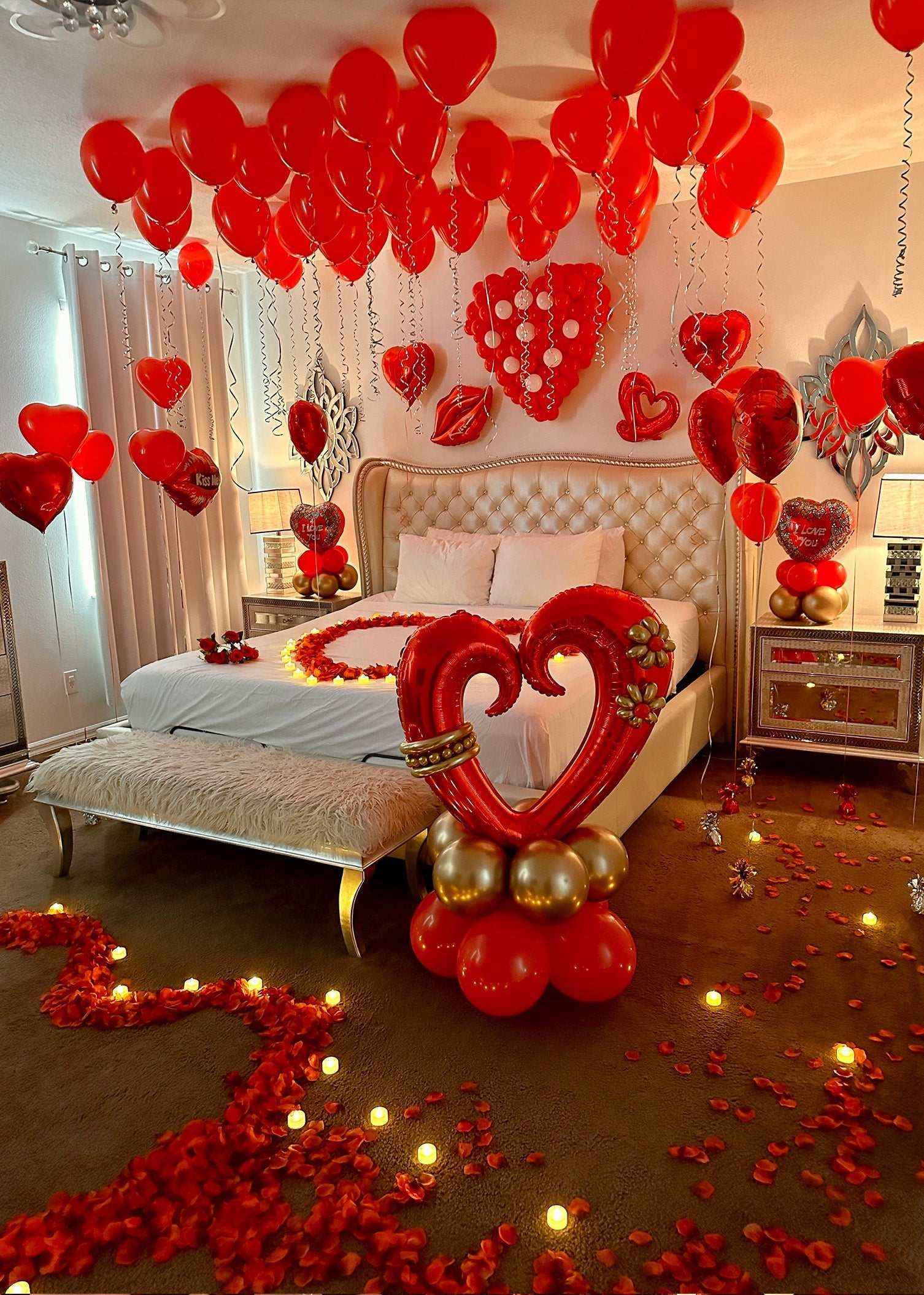 Romantic hotel room decorated with red heart-shaped balloons, rose petals, and LED lights for Crazy In Love Package celebration